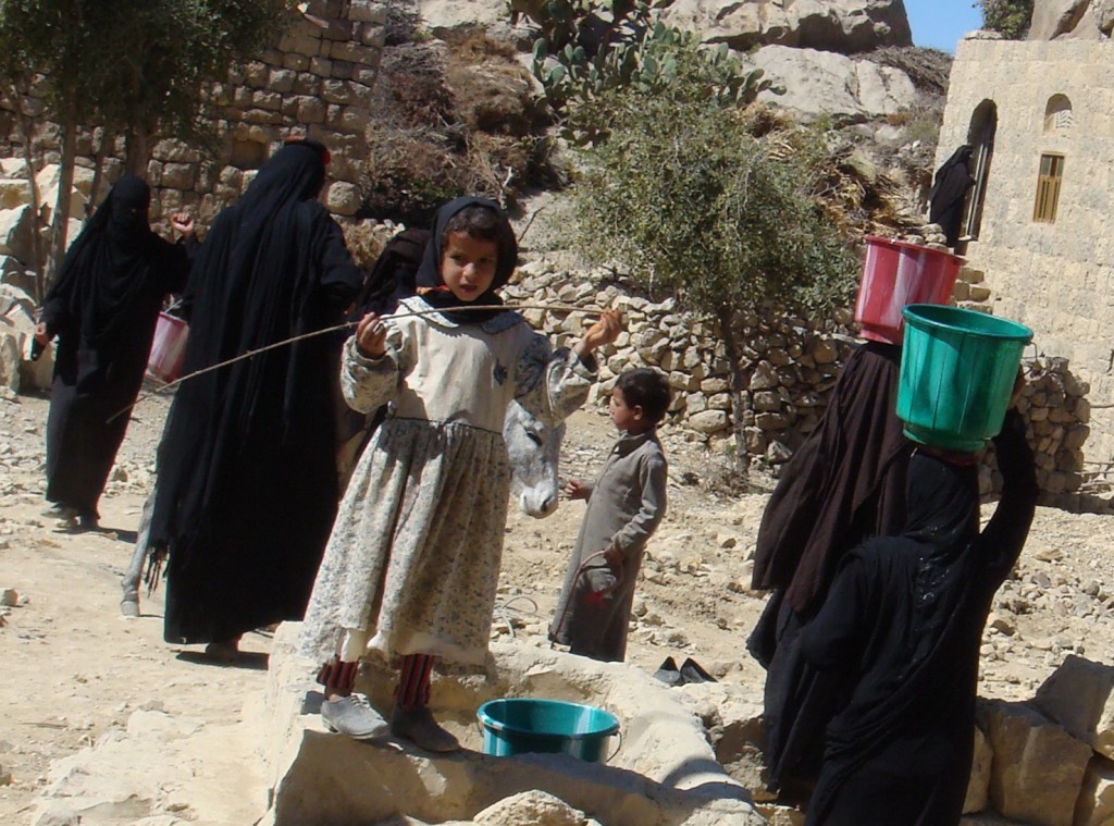 Children in Abyan, Yemen watch women bringing water from a well, built through donations of external funds and citizen volunteering.